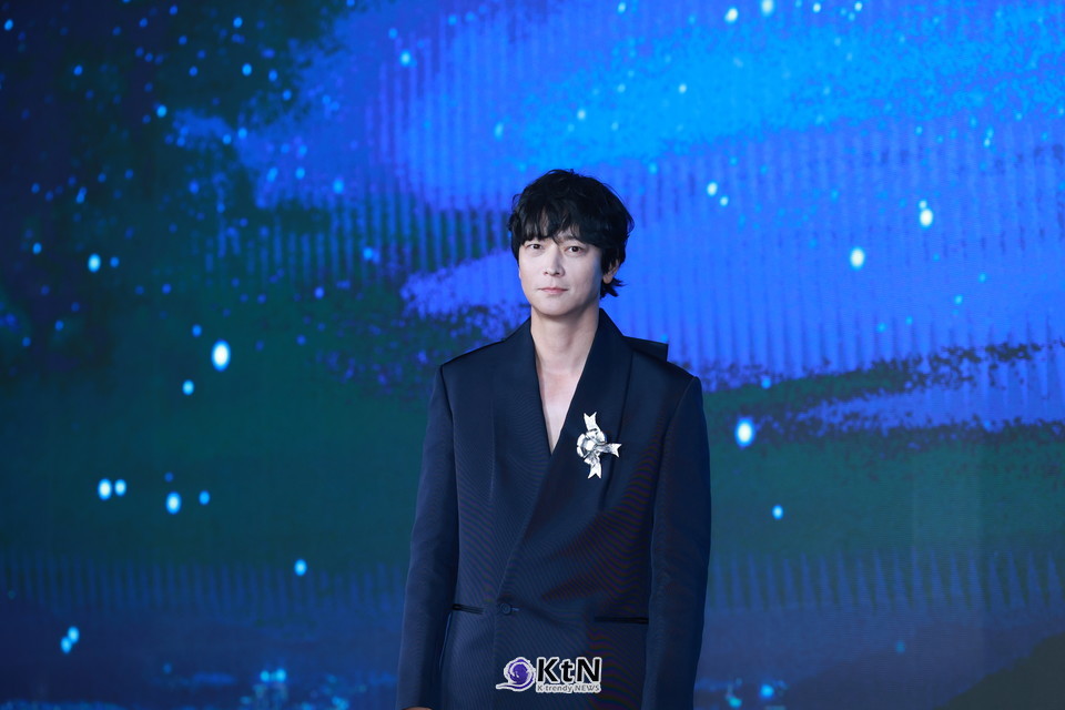 강동원은 네이비 테일러드 재킷+블랙 와이드 트라우저 조합에 실버 리본 브로치와 재킷 카라 뒤 대형(王) 리본을 더해, 미니멀 속 ‘한 방’을 보여줬다./사진=K trendy NEWS DB ⓒ케이 트렌디뉴스 무단전재 및 수집, 재배포금지