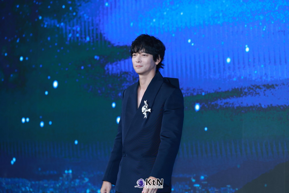 강동원은 네이비 테일러드 재킷+블랙 와이드 트라우저 조합에 실버 리본 브로치와 재킷 카라 뒤 대형(王) 리본을 더해, 미니멀 속 ‘한 방’을 보여줬다./사진=K trendy NEWS DB ⓒ케이 트렌디뉴스 무단전재 및 수집, 재배포금지