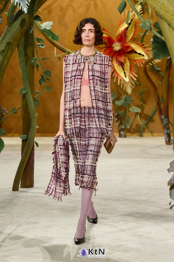 체크 수트와 손에 든 동화책이 샤넬 오트쿠튀르의 출발점을 보여준다.. Fairy Tale or Everyday Adventure? The Chanel "Gaby and the Beanstalk" Collection Rewrites Haute Couture. 사진=Chanel, K trendy NEWS DB ⓒ케이 트렌디뉴스 무단전재 및 수집, 재배포금지