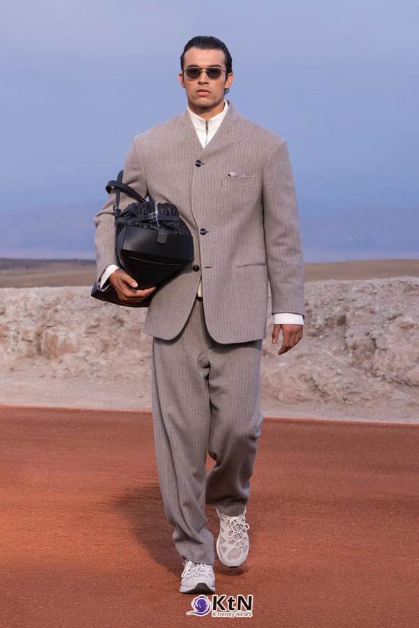 그레이 헤링본 스탠드칼라 재킷과 와이드 팬츠를 조합한 Giorgio Armani × Kith FW26 착장. 목둘레를 간결하게 정리한 칼라와 길게 내려오는 소매, 넓은 바지에 흰 셔츠와 밝은 스니커즈, 검은 가죽 가방을 더했다. 사진=Kith and Giorgio Armani, K trendy NEWS DB ⓒ케이 트렌디뉴스 무단전재 및 수집, 재배포금지