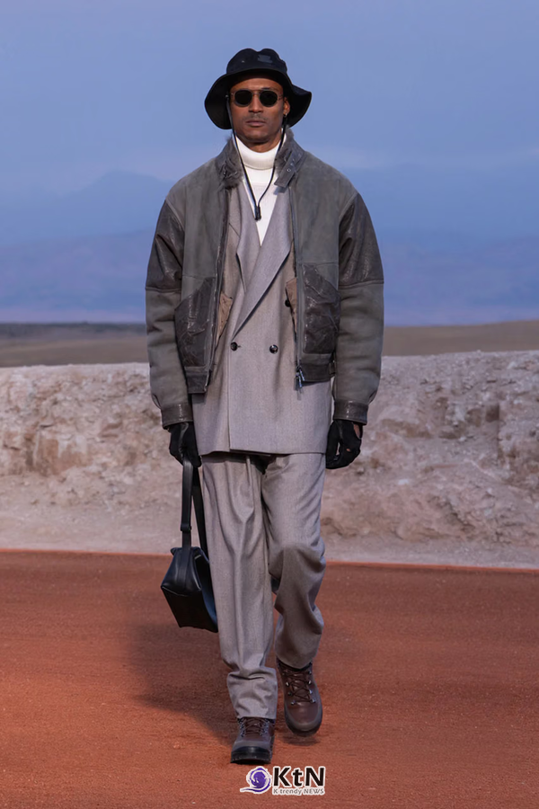그레이 더블브레스티드 수트 위에 짙은 그레이 스웨이드 블루종을 겹친 Giorgio Armani × Kith FW26 착장. 짧은 아우터와 길게 내려오는 수트 재킷, 넓은 팬츠에 버킷햇과 장갑, 가방과 부츠를 조합해 다층적인 실루엣을 완성했다. 사진=Kith and Giorgio Armani, K trendy NEWS DB ⓒ케이 트렌디뉴스 무단전재 및 수집, 재배포금지