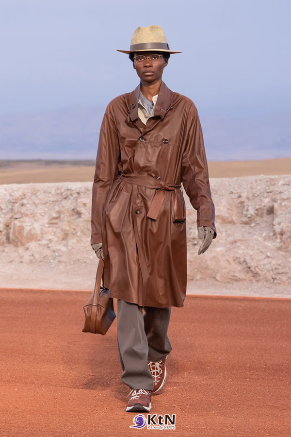 광택 있는 브라운 가죽 트렌치코트에 허리 벨트를 묶고 그레이 팬츠를 조합한 Giorgio Armani × Kith FW26 'Dreams of the Dune'. 넓은 칼라와 무릎 위까지 내려오는 코트, 밀짚 페도라와 장갑이 클래식한 사파리 아우터의 형태를 강조한다. 사진=Kith and Giorgio Armani, K trendy NEWS DB ⓒ케이 트렌디뉴스 무단전재 및 수집, 재배포금지