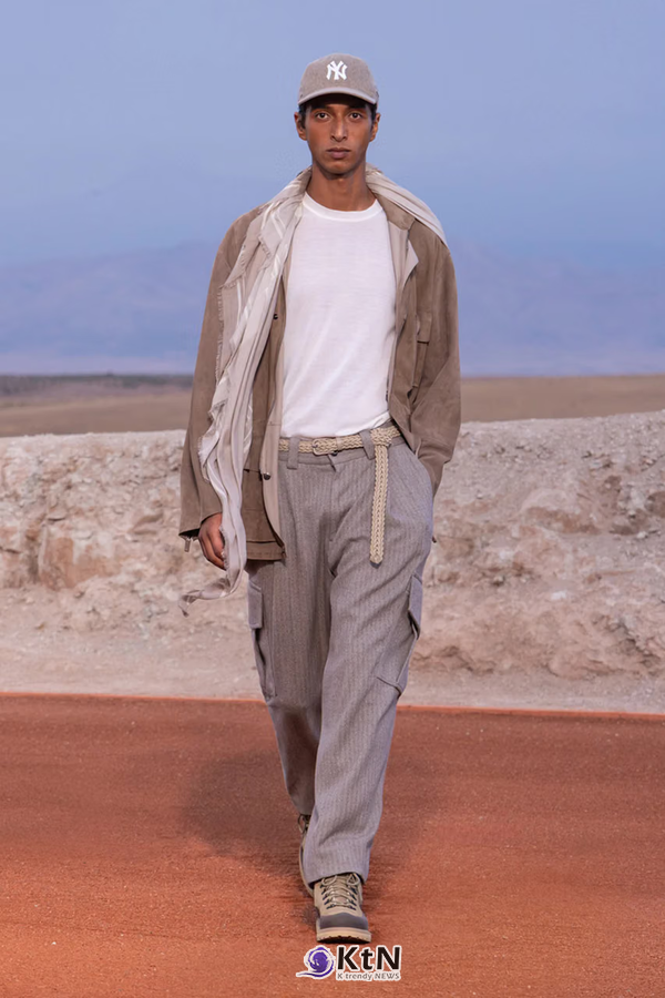 토프 컬러 셔츠 재킷에 흰 티셔츠와 그레이 헤링본 카고 팬츠를 조합한 Giorgio Armani × Kith FW26 착장. 뉴욕 양키스 캡과 브레이디드 벨트, 캐주얼 슈즈를 더해 유틸리티웨어의 포켓과 넓은 팬츠를 일상적인 스타일로 구성했다. 사진=Kith and Giorgio Armani, K trendy NEWS DB ⓒ케이 트렌디뉴스 무단전재 및 수집, 재배포금지