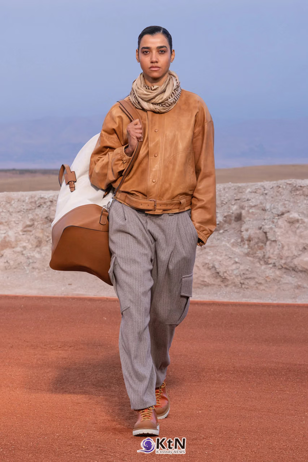 탄 컬러 가죽 블루종에 그레이 헤링본 카고 팬츠를 조합한 Giorgio Armani × Kith FW26 'Dreams of the Dune'. 목에 두른 뉴트럴 톤 스카프와 브라운·크림색 여행 가방, 탄 컬러 신발이 가죽의 질감과 넓은 팬츠의 비율을 강조한다. 사진=Kith and Giorgio Armani, K trendy NEWS DB ⓒ케이 트렌디뉴스 무단전재 및 수집, 재배포금지