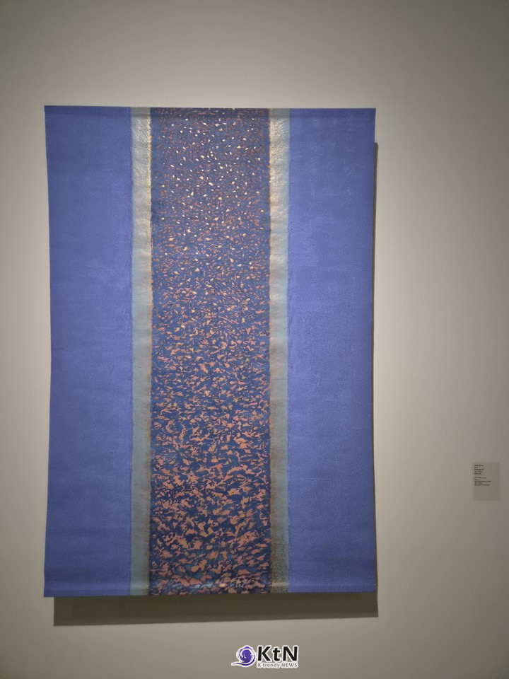 방혜자, ‘빛에서 빛으로’, 2014, 닥지에 천연안료, 180×120㎝, 방혜자재단. 넓은 푸른 영역 사이의 짙은 세로 띠에 주황·붉은빛의 작은 색 흔적이 밀집해 있다. 원형의 확산에서 벗어나 수많은 색의 입자와 수직의 흐름으로 빛을 풀어낸 후기 작업이다. 사진= K trendy NEWS DB ⓒ케이 트렌디뉴스 무단전재 및 수집, 재배포금지 