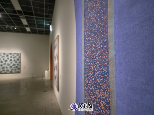 방혜자, ‘빛에서 빛으로’, 2014, 닥지에 천연안료, 180×120㎝, 방혜자재단. 넓은 푸른 영역 사이의 짙은 세로 띠에 주황·붉은빛의 작은 색 흔적이 밀집해 있다. 원형의 확산에서 벗어나 수많은 색의 입자와 수직의 흐름으로 빛을 풀어낸 후기 작업이다. 사진= K trendy NEWS DB ⓒ케이 트렌디뉴스 무단전재 및 수집, 재배포금지 